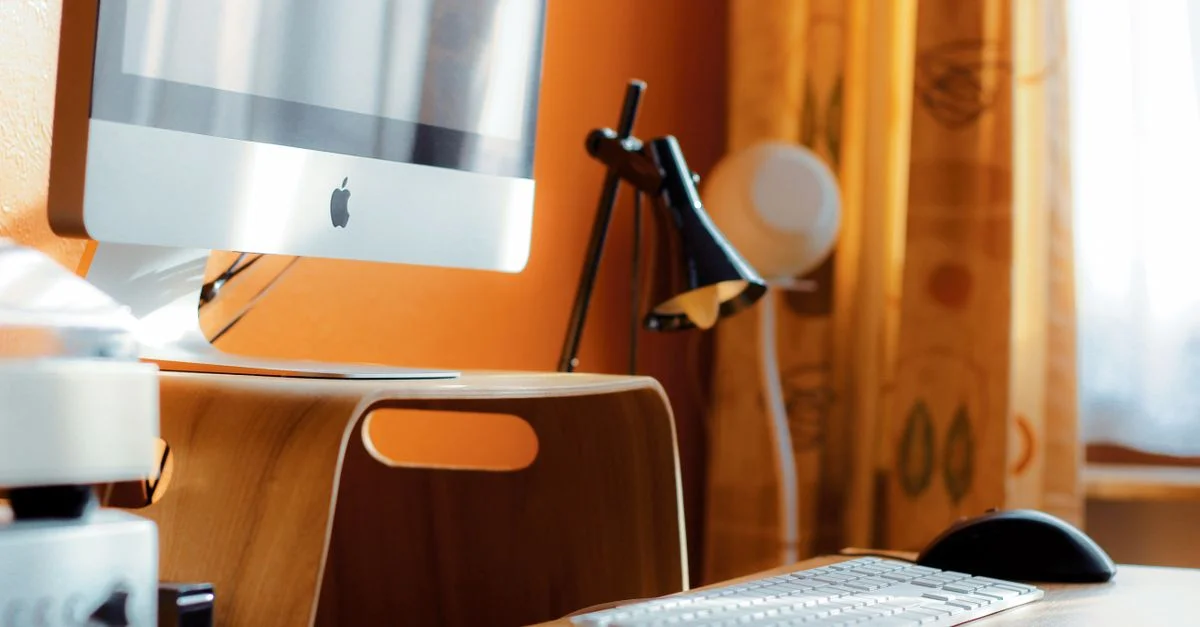 Aménagement de bureau moderne avec un ordinateur et une lampe de bureau sur une table en bois.