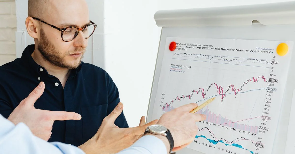 Des professionnels de l'entreprise discutent de graphiques financiers sur un paperboard lors d'une réunion en journée.