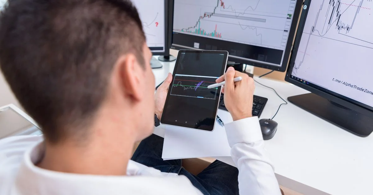 Un trader examinant des graphiques de cryptomonnaies sur une tablette dans un bureau moderne.